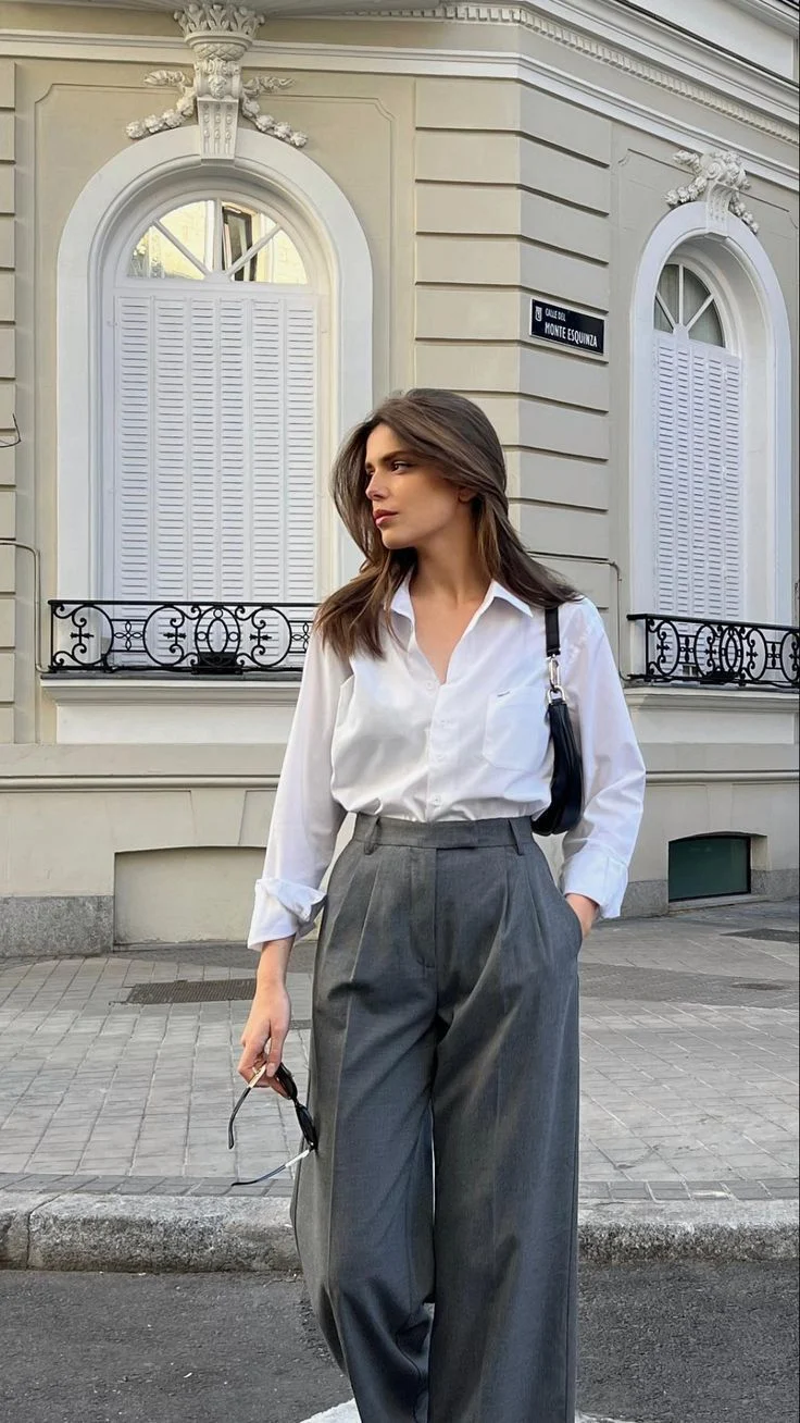 Minimalist city outfit with white oversized shirt grey wide leg pants and European architecture